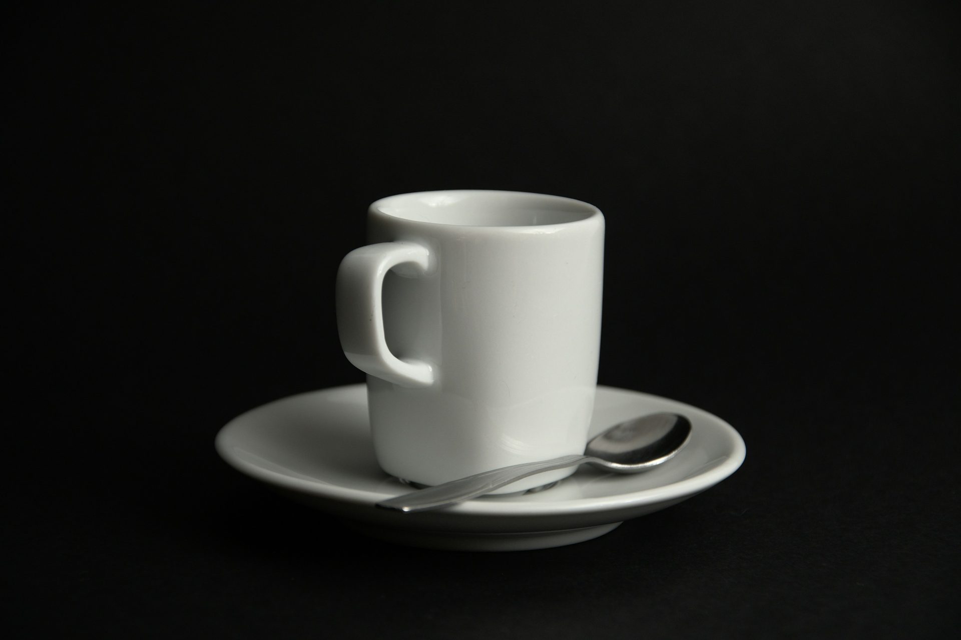 a white cup and saucer with a spoon